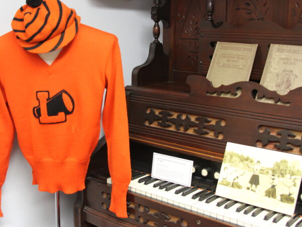 display of an orange shirt, antique piano, old photos etc.