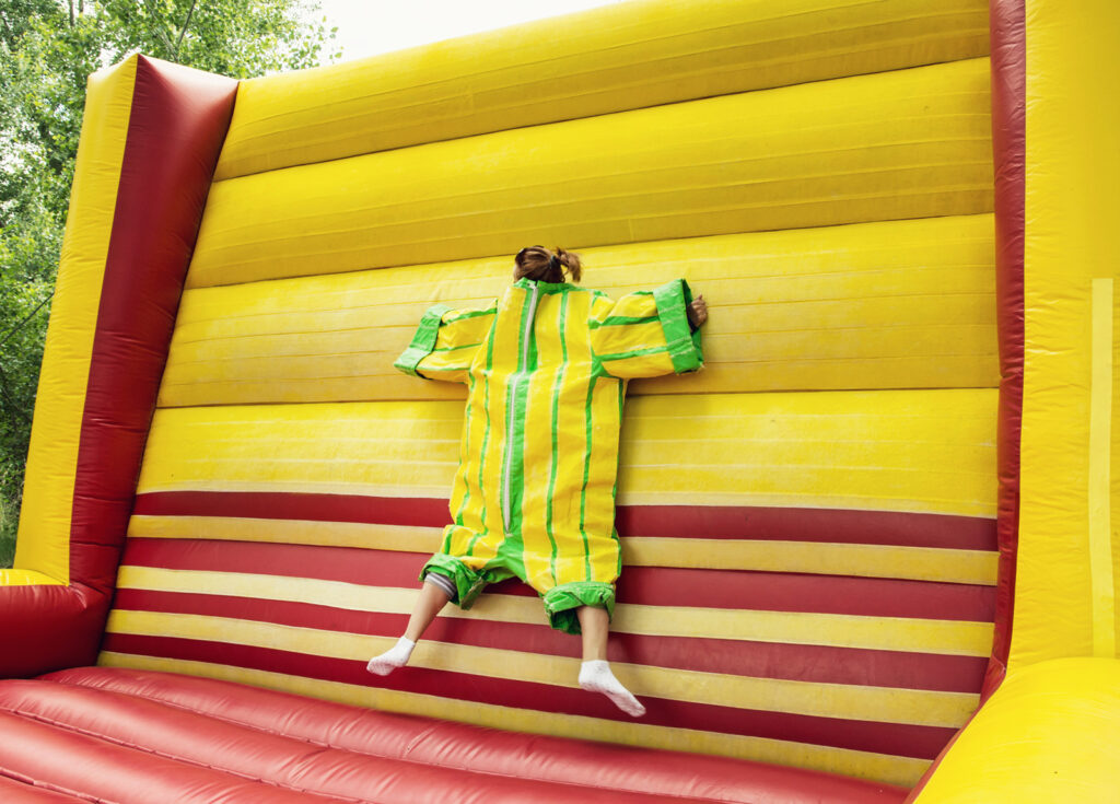 young person stuck on inflatable velcro wall