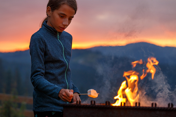 teen roasting a marshmellow at a sunset