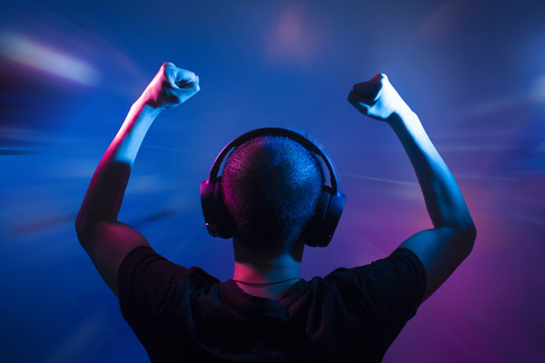teen with arms raised in victory and wearing gamer headphones