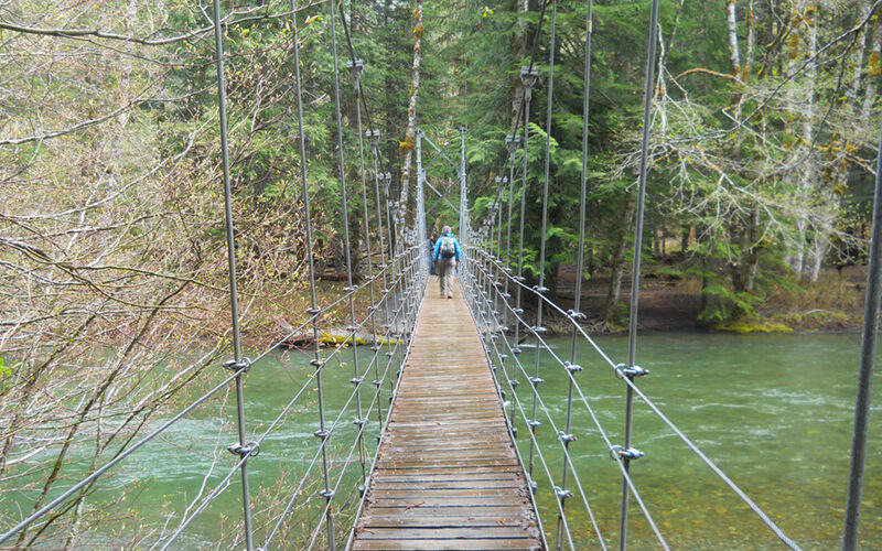 person walking across a suspension bridge