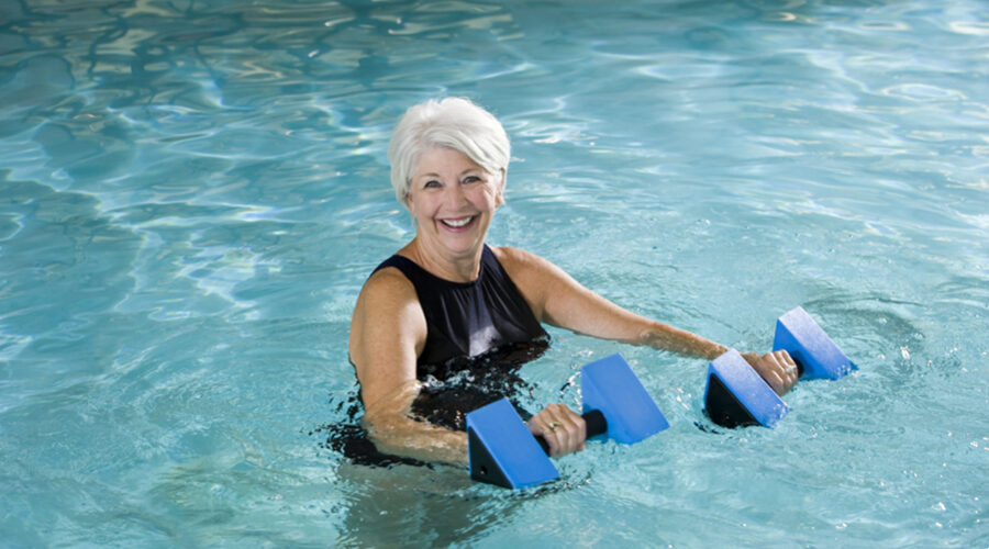 older woman in pool with weights