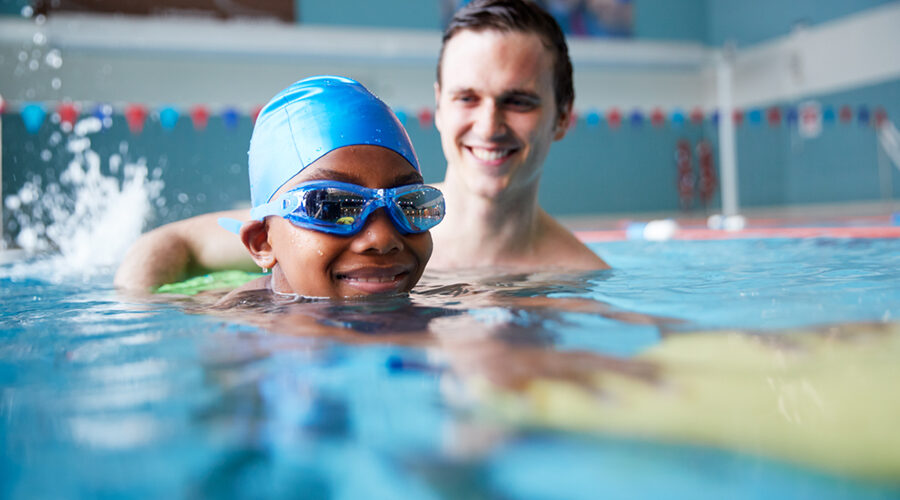 a kid with a swimming instructor learning to swim