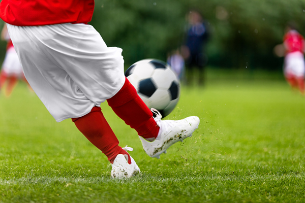 soccer player's feet kicking the ball on green turf